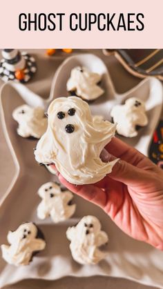 a hand holding a ghost cupcake with white frosting