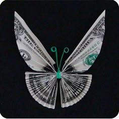 a butterfly made out of dollar bills sitting on top of a black surface with words underneath it