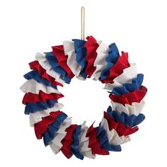 a wreath with red, white and blue ruffles hanging on a string next to a ruler