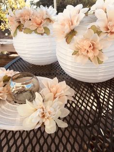 three white vases sitting on top of a table with flowers in them and plates