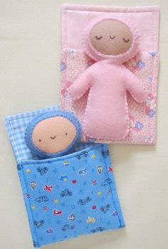 two small stuffed animals sitting next to each other on top of a bed covered in blue and pink sheets