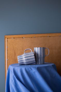 two cups sitting on top of a blue table cloth covered bed headboard and foot board