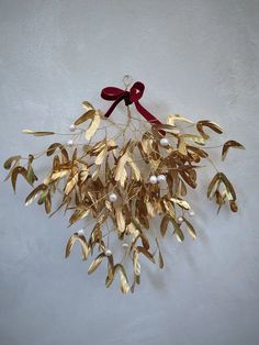 a bunch of gold leaves with a red bow hanging on the wall next to it