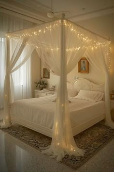 a white bed sitting in a bedroom next to a window with lights on top of it