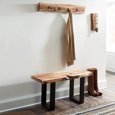 a wooden bench sitting next to a wall with two coats hanging on it's hooks