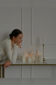 a woman leaning on a table next to candles