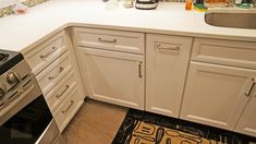 a kitchen with white cabinets and stainless steel stove top oven, sink and dishwasher