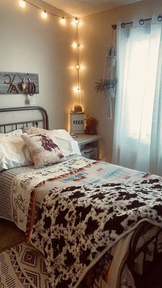 a bed sitting in a bedroom next to a window with lights on the side of it