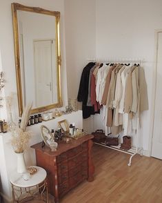 a room with a dresser, mirror and clothes rack