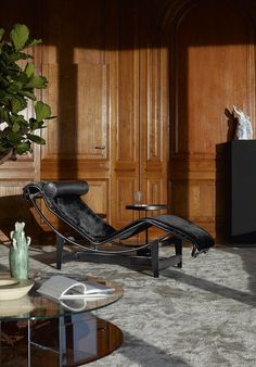 a living room filled with furniture and wooden paneled walls, along with a glass coffee table