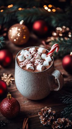 hot chocolate with marshmallows and candy cane in a mug surrounded by christmas decorations