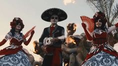 three people dressed in mexican style clothing and sombreros are dancing with each other