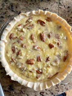 a pie sitting on top of a table next to a knife and bowl filled with nuts