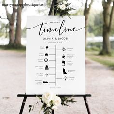 a wedding sign with flowers and greenery is displayed on an easel in front of trees