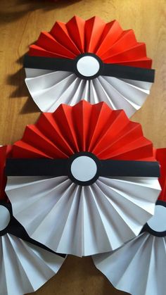 three red and white paper fans sitting on top of a wooden table