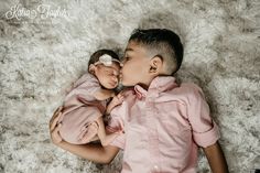 a couple of kids laying next to each other on top of a white rug together