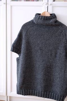 a gray sweater hanging on a white coat rack