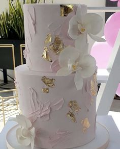 a pink and gold wedding cake with white flowers