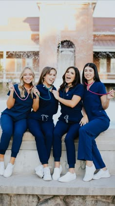 four women in scrubs pose for a photo near a fountain with water spouting from it