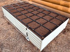 a white box with brown dirt in front of a log wall and wooden slats