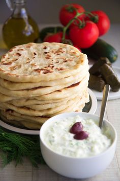 a stack of pita bread next to a bowl of yogurt