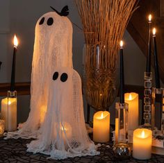 a table topped with lots of candles next to a tall spider web covered in black dots