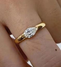 a woman's hand with a yellow gold ring and a white diamond on it