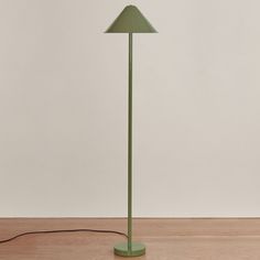 a green floor lamp sitting on top of a wooden table