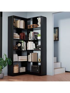 an open bookcase with many books on it in a living room next to a potted plant