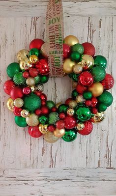 a christmas wreath hanging on the side of a wooden door decorated with ornaments and balls