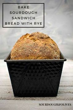 a loaf of sourdough sandwich bread in a black baking pan with the words, bake sourdough sandwich bread with rye