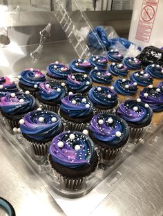 cupcakes with blue icing and white sprinkles are on display