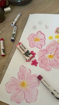 some crayons are laying on top of a piece of paper with flowers drawn on it