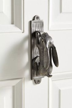 a metal hook on the side of a white door with an image of two birds