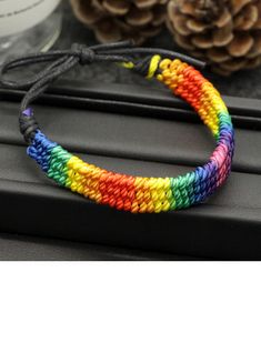 a rainbow bracelet on top of a black table next to pine cones and other items