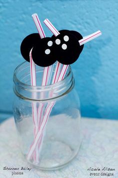 there are some paper straws in a jar with black and white decorations on it