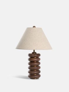 a lamp that is sitting on top of a white tablecloth with a brown base