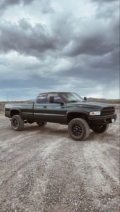 a black pickup truck parked on top of a dirt field