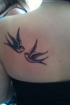 the back of a woman's shoulder with two birds tattoo on her left side