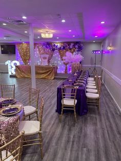 a banquet hall set up with purple and gold decorations, white chairs, and tables