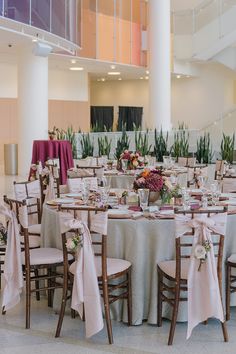 the tables are set up for an event with white linens and pink sashes