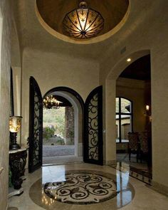 an entry way with arched doorways and chandelier on the ceiling is shown