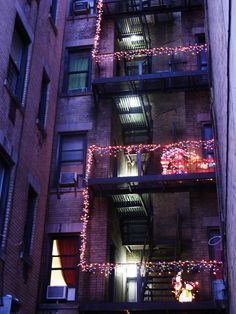 an apartment building with christmas lights on the balconies and balcony railings in new york city