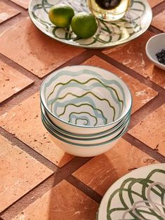 plates and bowls are sitting on the floor next to each other with limes in them