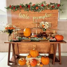 a table topped with lots of pumpkins next to a sign that says little pumpkin