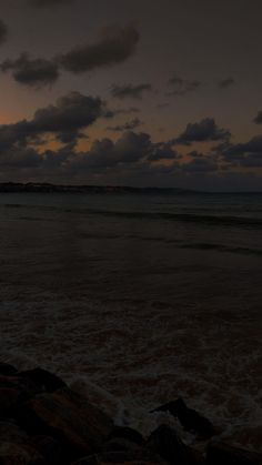 a person standing on the beach holding an umbrella at night with clouds in the background