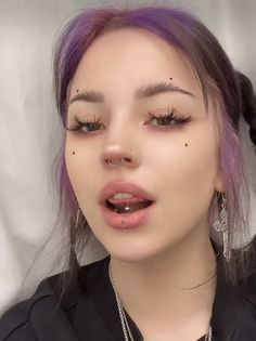 a woman with purple hair and piercings on her nose