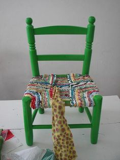 a stuffed giraffe sitting on top of a green chair next to a pile of cloth