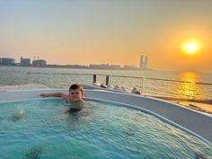 a young boy is swimming in an outdoor hot tub on the deck of a boat