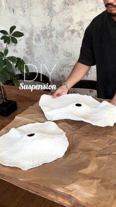 a man sitting at a table with two white vases in front of him on top of a brown paper bag